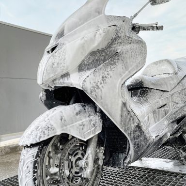 Ein Motorrad, das mit Schaum überzogen ist, steht in einer Waschstation.