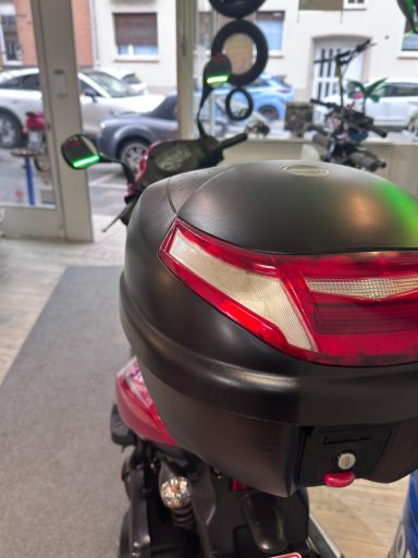 Motorrad mit rotem Rücklicht und grünen Blinker an einem Parkplatz.