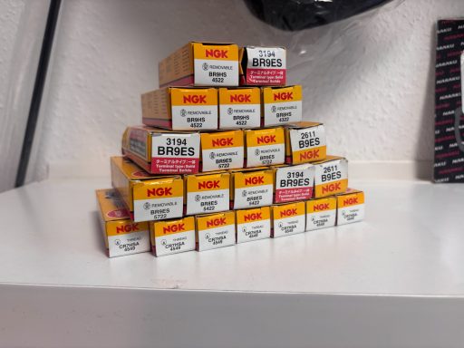 Stapelhaufen von Kartons mit verschiedenen Farben und Beschriftungen auf einer weißen Fläche.
