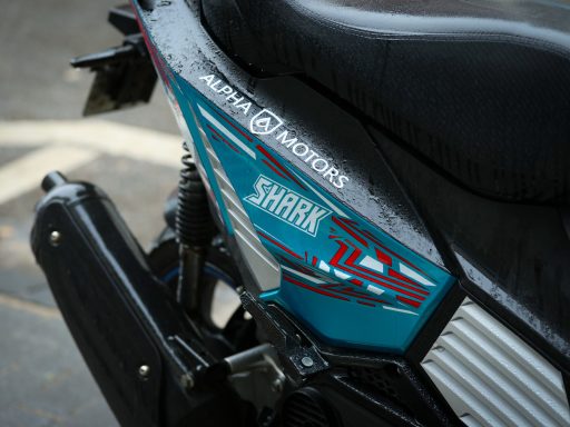 Nahaufnahme eines Motorrads mit dem Schriftzug "Shira" und modernem Design in Blau und Silber.
