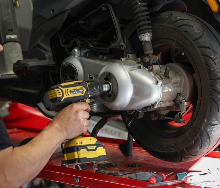 2TaktGarage Krefeld: Ersatzteile, Flüssigkeiten, Inspektionen mann schraubt an einem motorroller in einer garage